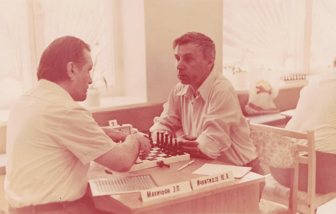 Юрий Акакьевич за шахматной доской; на столе видна табличка с его фамилией
